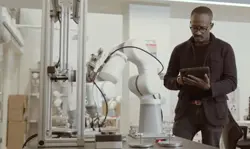 A man in a lab coat uses a tablet to control an advanced robotic arm in a modern laboratory filled with cutting-edge technical equipment. Sourcing, Procurement, 3rd Party Risk