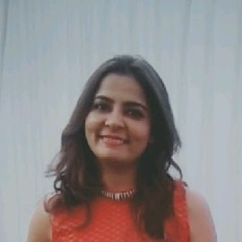 A woman with shoulder-length dark hair wears a sleeveless red textured top and a necklace, smiling warmly in front of a light-colored curtain background. Sourcing, Procurement, 3rd Party Risk