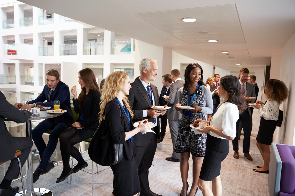 Business professionals in formal attire network, enjoy refreshments, and converse in a modern office hallway during a corporate event. Sourcing, Procurement, 3rd Party Risk