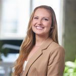 A young woman with long blonde hair, blue eyes, and a bright smile, wearing a tan blazer over a white shirt, radiates confidence—perfectly embodying the professionalism often seen in procurement roles. Sourcing, Procurement, 3rd Party Risk