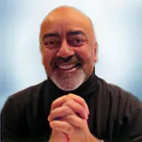 A smiling man with a bald head and gray beard, wearing a black turtleneck, sits with his hands clasped together in front of a light blue background. Sourcing, Procurement, 3rd Party Risk