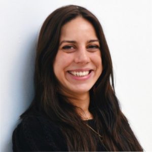 Woman with long dark hair wearing a black top, smiling at the camera, standing against a plain white background. Sourcing, Procurement, 3rd Party Risk