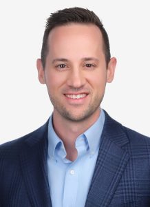 Smiling man with short dark hair wearing a blue blazer and light blue shirt against a plain white background. Sourcing, Procurement, 3rd Party Risk