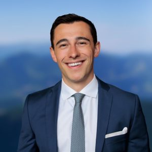 A man in a blue suit, white shirt, and grey tie smiling at the camera. Sourcing, Procurement, 3rd Party Risk