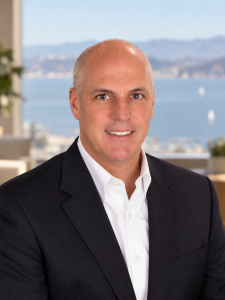 A smiling man with a shaved head wearing a dark blazer and white dress shirt. Sourcing, Procurement, 3rd Party Risk
